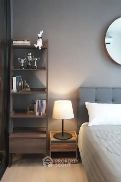 Modern bedroom with stylish decor, featuring a cozy bed, elegant lamp, and chic shelving unit.