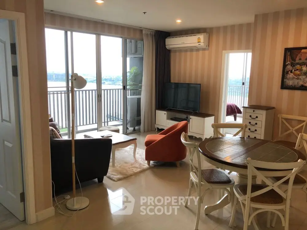 Spacious living room with modern furniture and large windows offering stunning river view.
