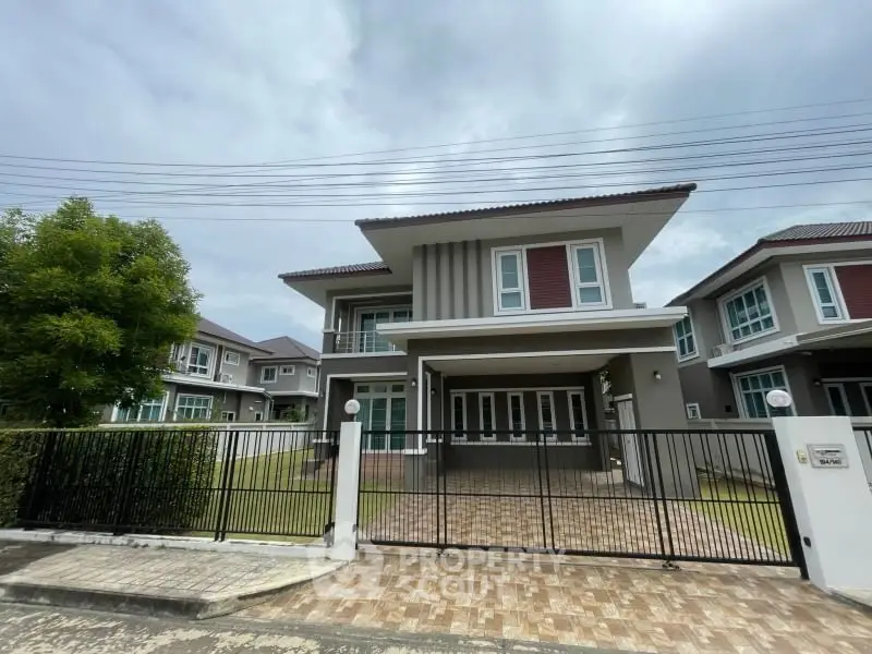 Modern two-story house with gated entrance and spacious driveway in a suburban neighborhood.