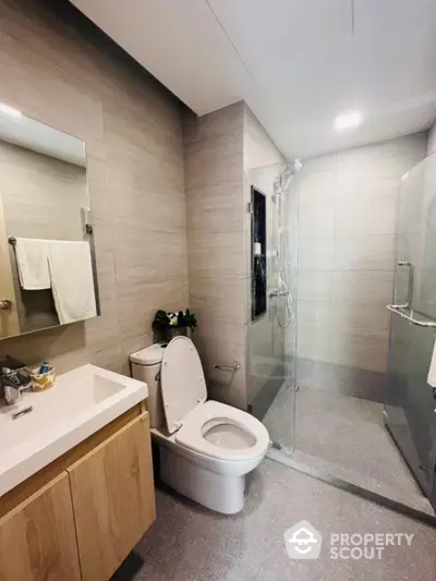 Modern bathroom with glass shower and sleek vanity in contemporary apartment.