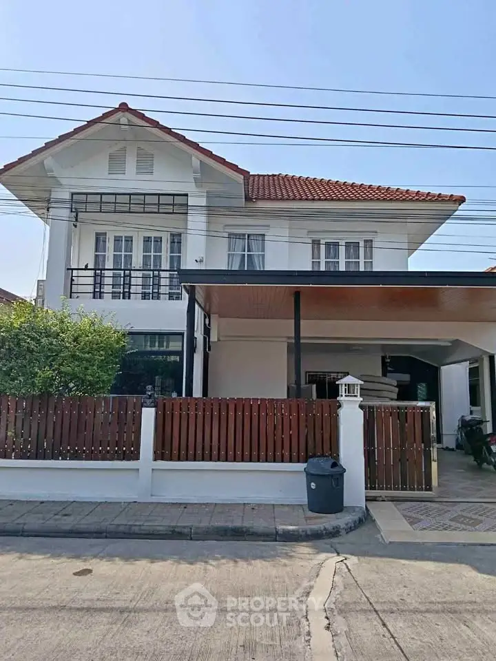 Charming two-story house with red roof and spacious carport in a serene neighborhood.