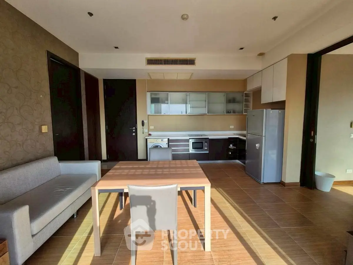 Modern open-layout kitchen and living area with natural light and sleek furnishings.