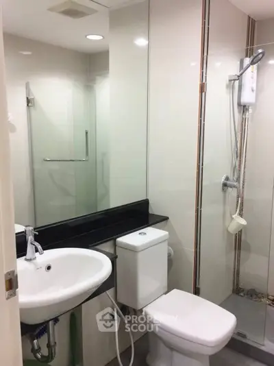 Modern bathroom with sleek fixtures and glass shower enclosure in a contemporary apartment.