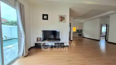 Spacious living room with pool view and modern kitchen in open layout home.