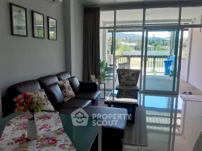 Spacious living room with modern decor and large balcony offering scenic views.