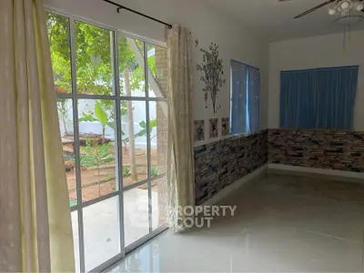 Bright room with large windows overlooking a garden, featuring elegant curtains and decorative wall accents.