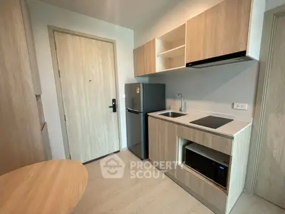 Modern compact kitchen with sleek appliances and wooden cabinetry in a cozy apartment.