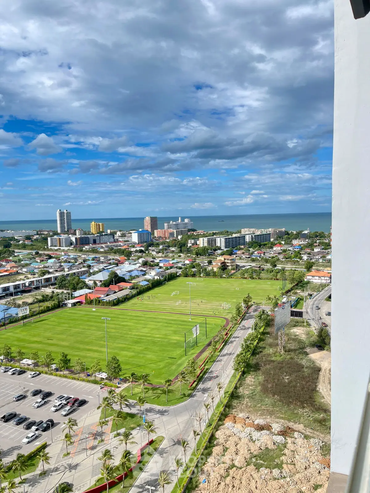 Stunning cityscape view with lush greenery and ocean horizon from high-rise building.