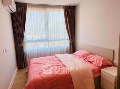 Cozy bedroom with pink bedding and large window offering natural light