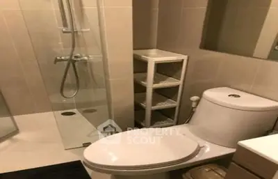 Modern bathroom with glass shower and sleek fixtures in contemporary apartment.