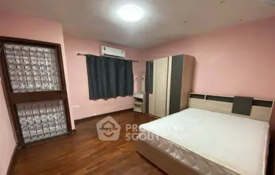 Spacious bedroom with wooden flooring and modern furniture in a cozy apartment.