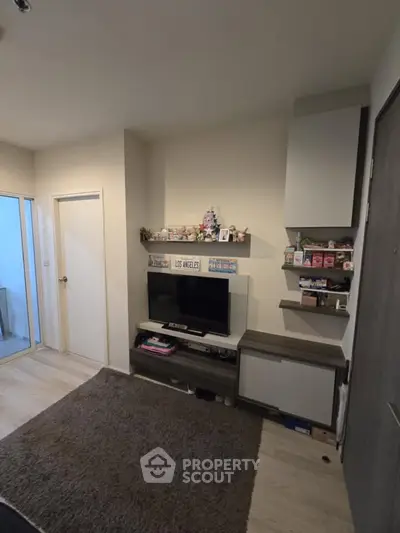 Cozy living room with modern TV setup and stylish shelving in a compact space.