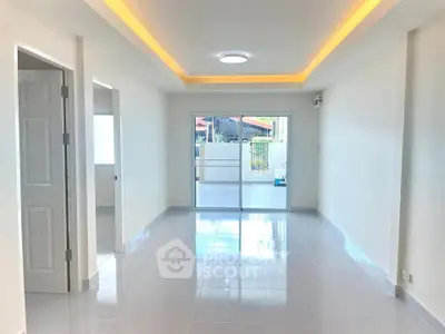 Spacious modern living room with sleek flooring and large sliding glass doors leading to a balcony.