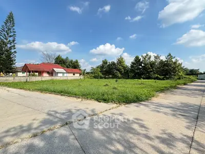 Spacious vacant land with lush greenery and clear blue sky, perfect for development opportunities.
