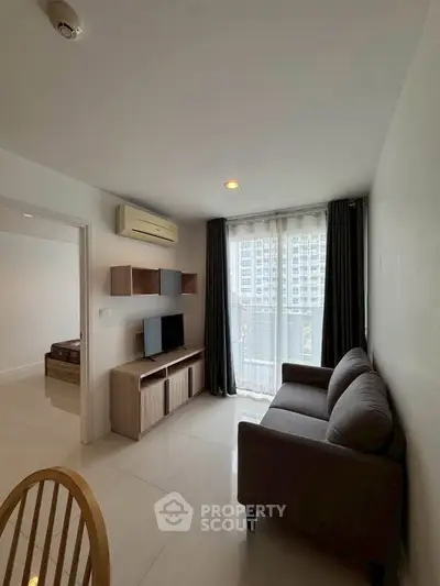 Modern living room with balcony view, featuring sleek furniture and natural light.