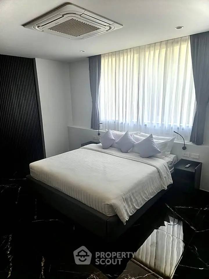 Luxurious bedroom with elegant decor and natural light, featuring a comfortable bed and stylish curtains.