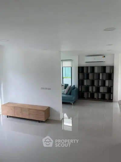Modern living room with sleek furniture and minimalist design, featuring a cozy sofa and stylish shelving unit.