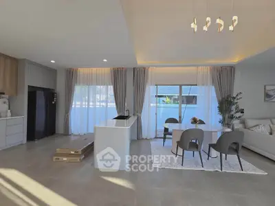 Spacious modern living room with open kitchen and elegant dining area, featuring large windows and stylish decor.