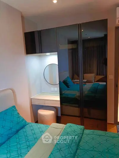 Modern bedroom with stylish mirrored wardrobe and cozy bed setup.