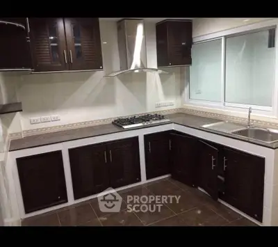 Modern kitchen with dark cabinets, gas stove, and sleek countertops in a stylish home.