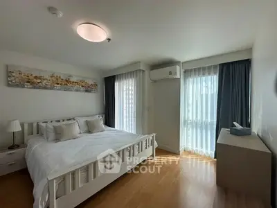Spacious bedroom with natural light, modern decor, and wooden flooring in a stylish apartment.
