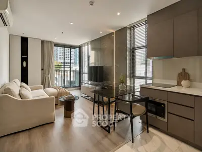 Modern living room with open kitchen, featuring sleek furniture and large windows for natural light.