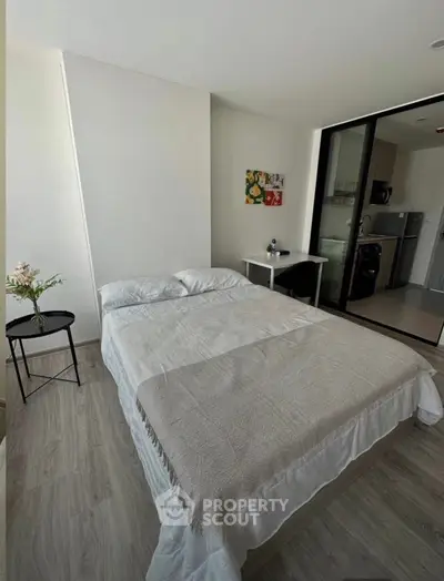 Modern bedroom with cozy bed and kitchenette in open layout apartment