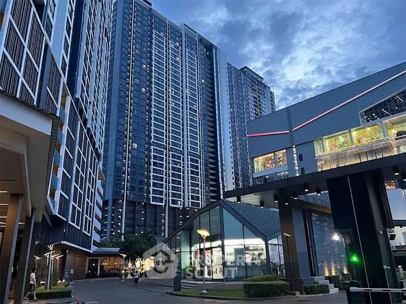 Modern high-rise residential complex with sleek architecture and urban amenities at dusk.