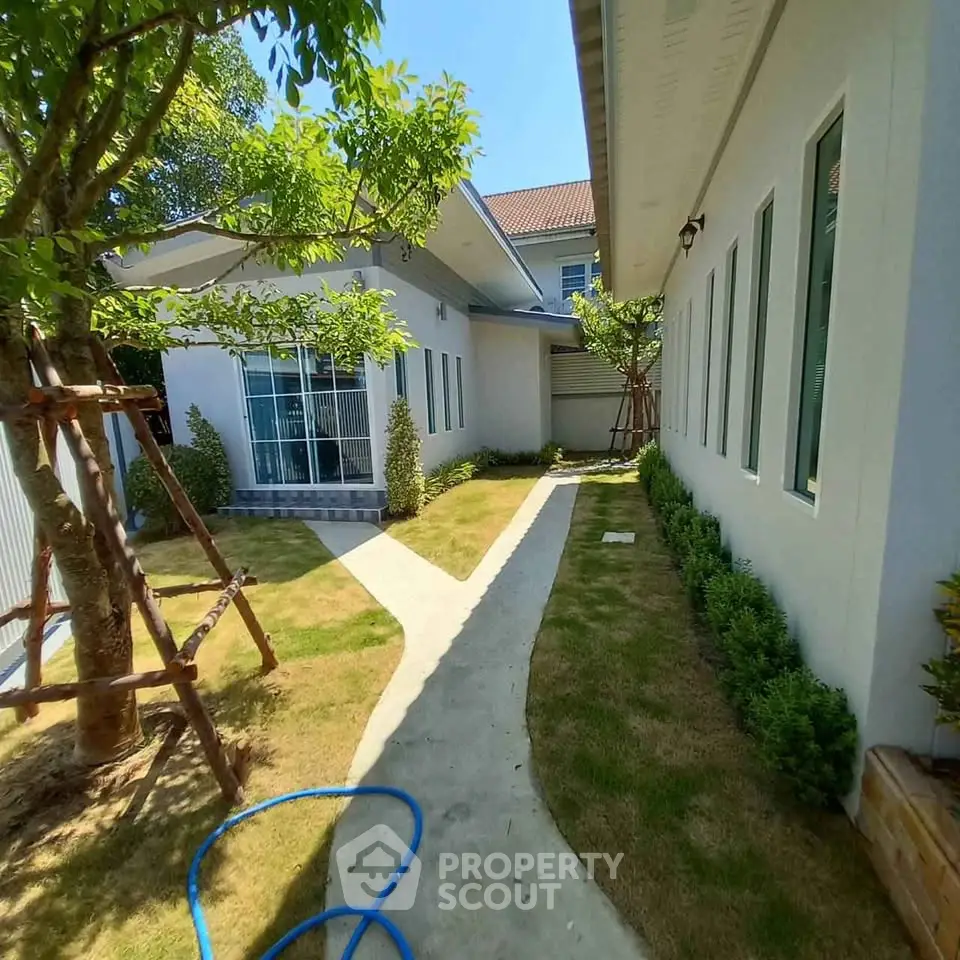 Charming garden view of modern home with lush greenery and inviting pathway, perfect for serene outdoor living.