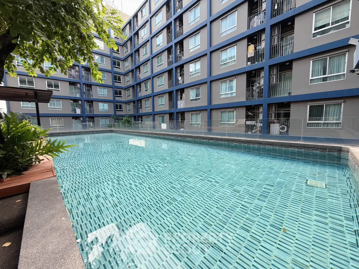 Modern apartment building with a sparkling outdoor pool and lush greenery.