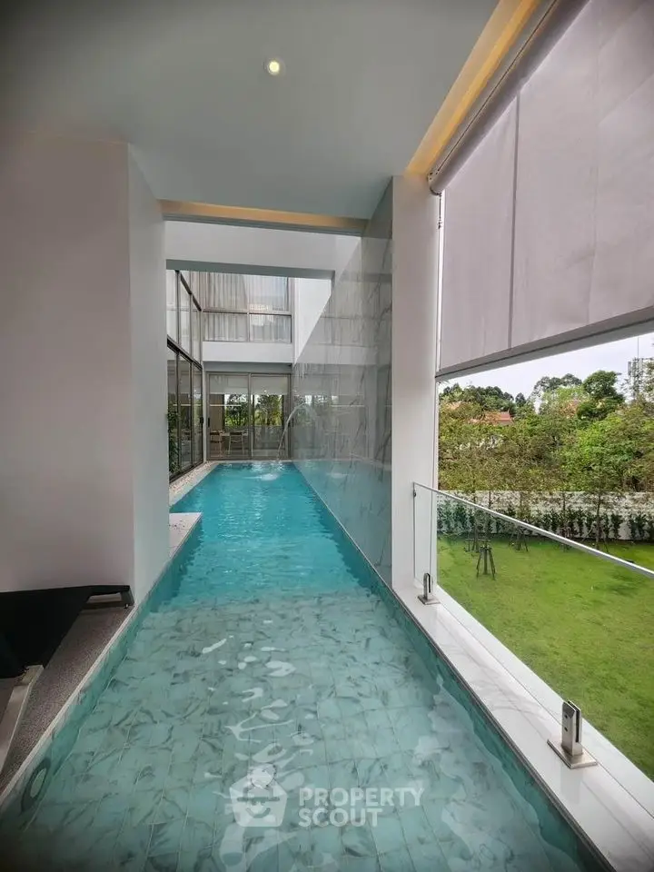 Luxurious indoor pool with glass walls overlooking lush garden