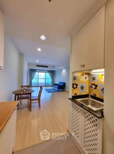 Spacious open-plan living room with stylish kitchen and large window view.