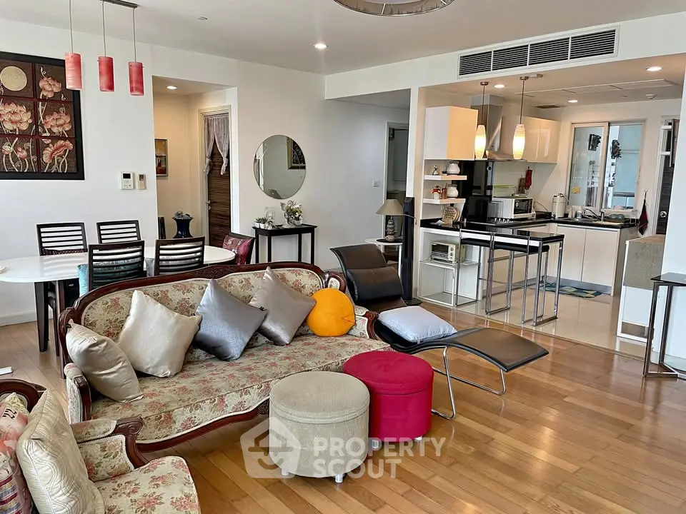 Spacious living room with elegant decor and open kitchen layout, featuring hardwood floors and modern furnishings.