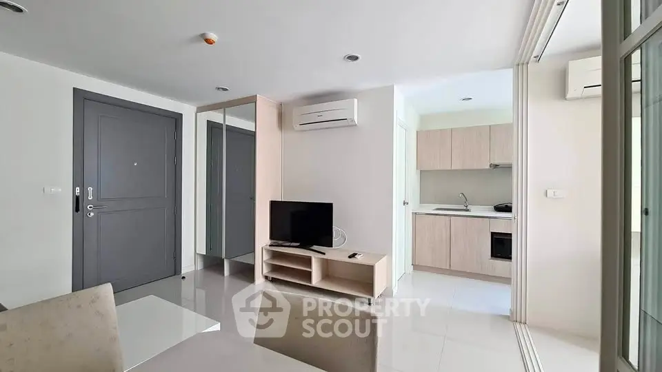 Modern apartment interior with sleek kitchen and cozy living area, featuring air conditioning and stylish decor.
