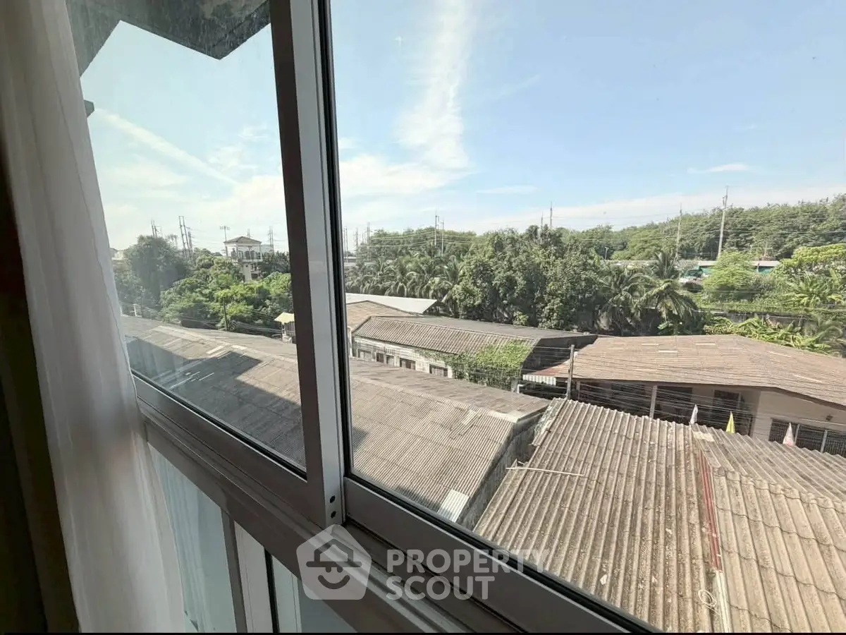 Scenic view from a window overlooking rooftops and lush greenery, perfect for nature lovers.