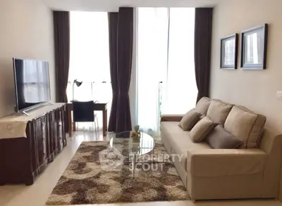 Elegant living room with modern sofa, large TV, and stylish decor in a bright apartment.