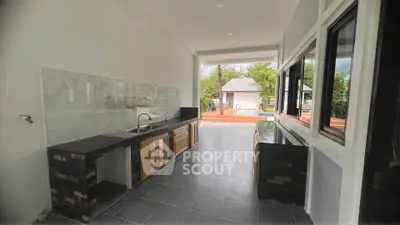 Modern open kitchen with sleek design and poolside view, perfect for entertaining.