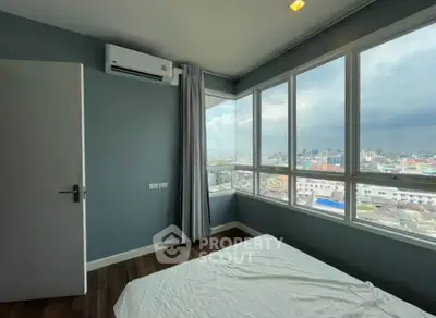 Spacious bedroom with large windows offering stunning city views, perfect for urban living.