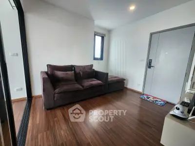 Modern living room with sleek wooden flooring and cozy brown sofa in a stylish apartment.