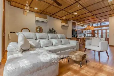 Spacious living room with modern decor and open kitchen layout, featuring cozy seating and natural light.