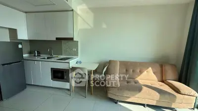 Modern studio apartment with compact kitchen and cozy living area, featuring sleek cabinetry and natural light.