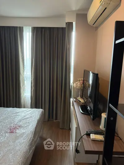 Cozy bedroom with modern furnishings and natural light from large window, perfect for relaxation.