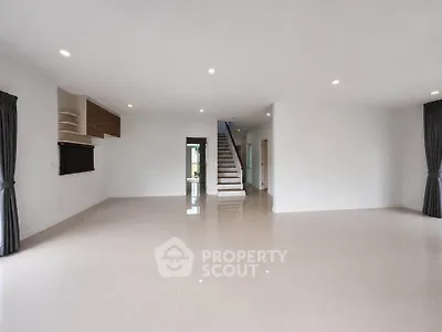 Spacious modern living room with sleek tile flooring and elegant staircase in open-concept home.