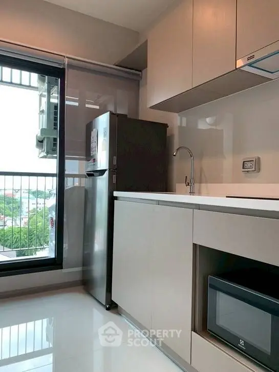 Modern kitchen with sleek cabinetry and stainless steel appliances, featuring a large window with a view.
