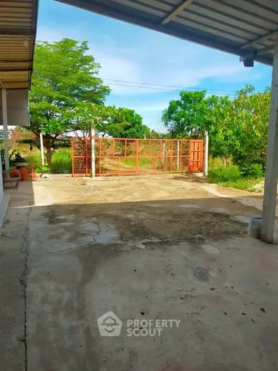 Spacious outdoor area with gated entrance and lush greenery, perfect for residential or commercial use.
