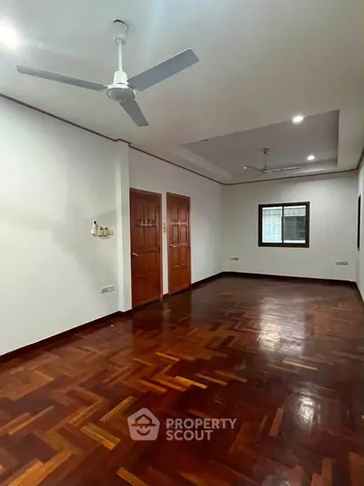 Spacious room with elegant wooden flooring and ceiling fan, perfect for a cozy living space.