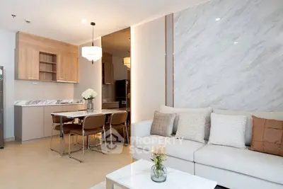 Modern open-plan living room with elegant kitchen and cozy seating area, featuring stylish decor and natural lighting.