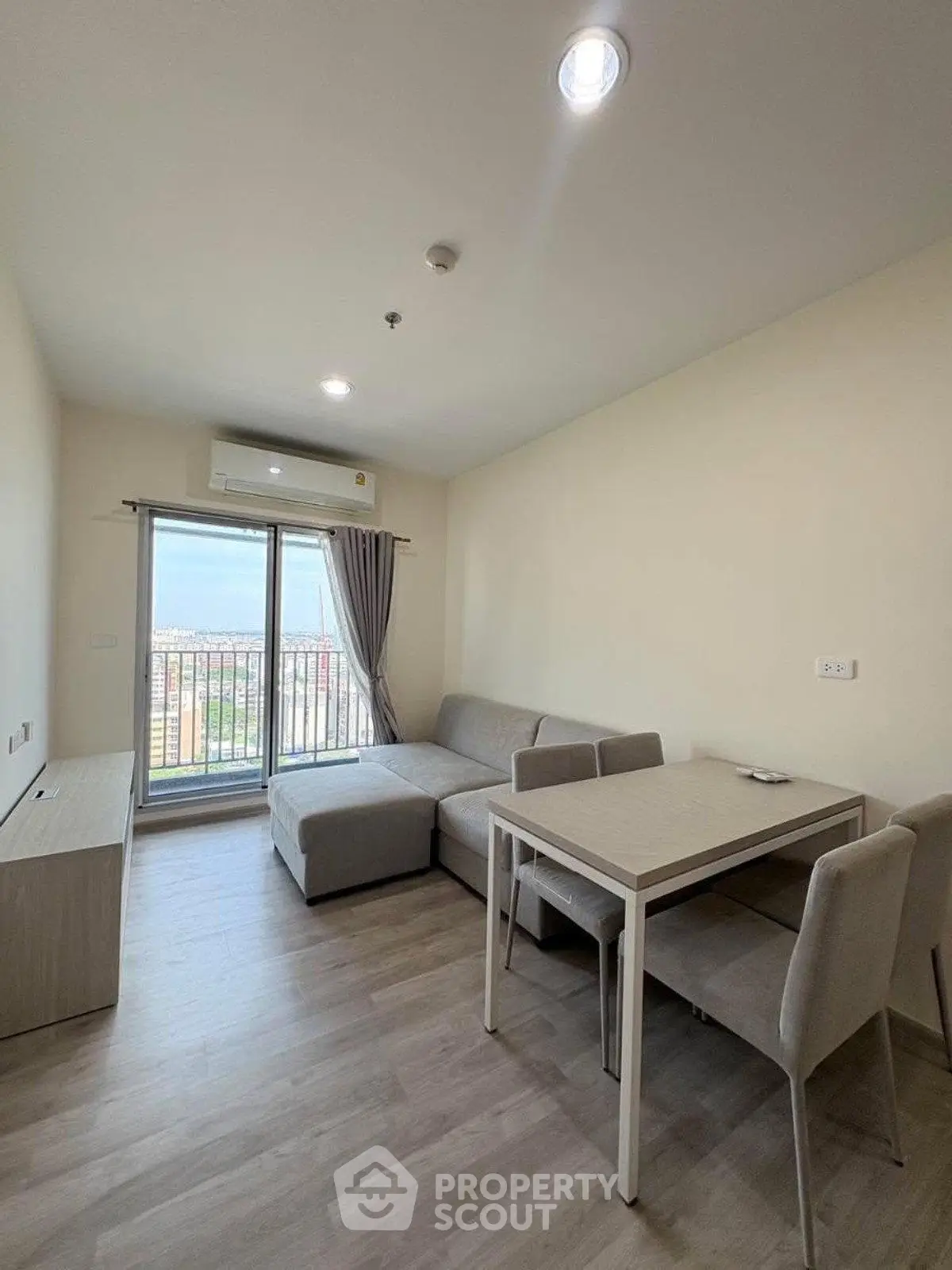 Modern living room with cozy sofa and dining area, featuring a large window with city view.