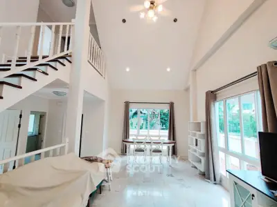 Spacious living room with high ceilings and elegant staircase in modern home