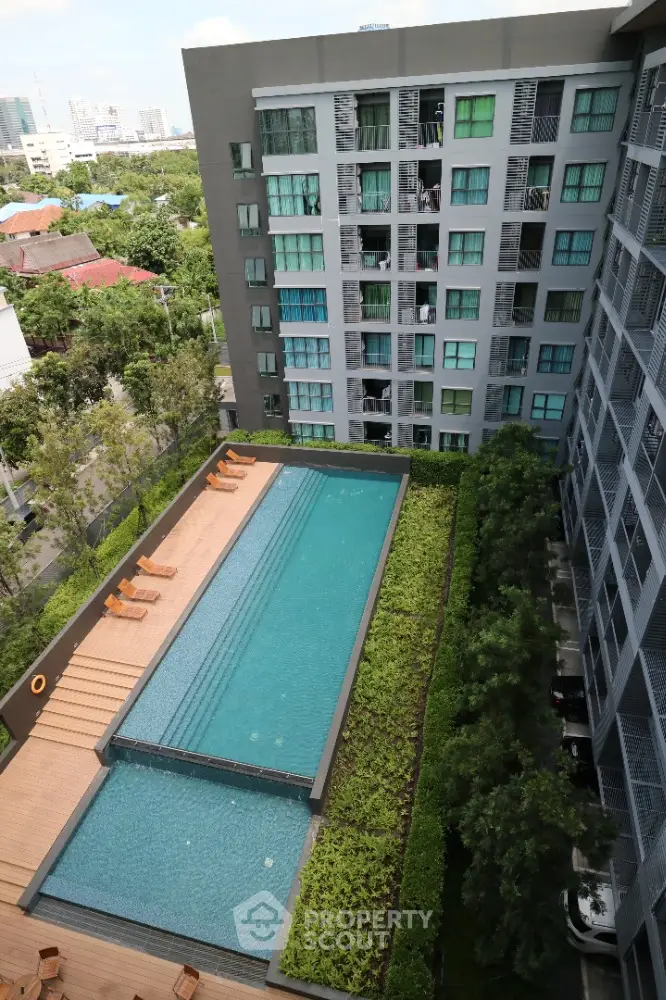 Modern condominium with rooftop pool and lush greenery in urban setting.